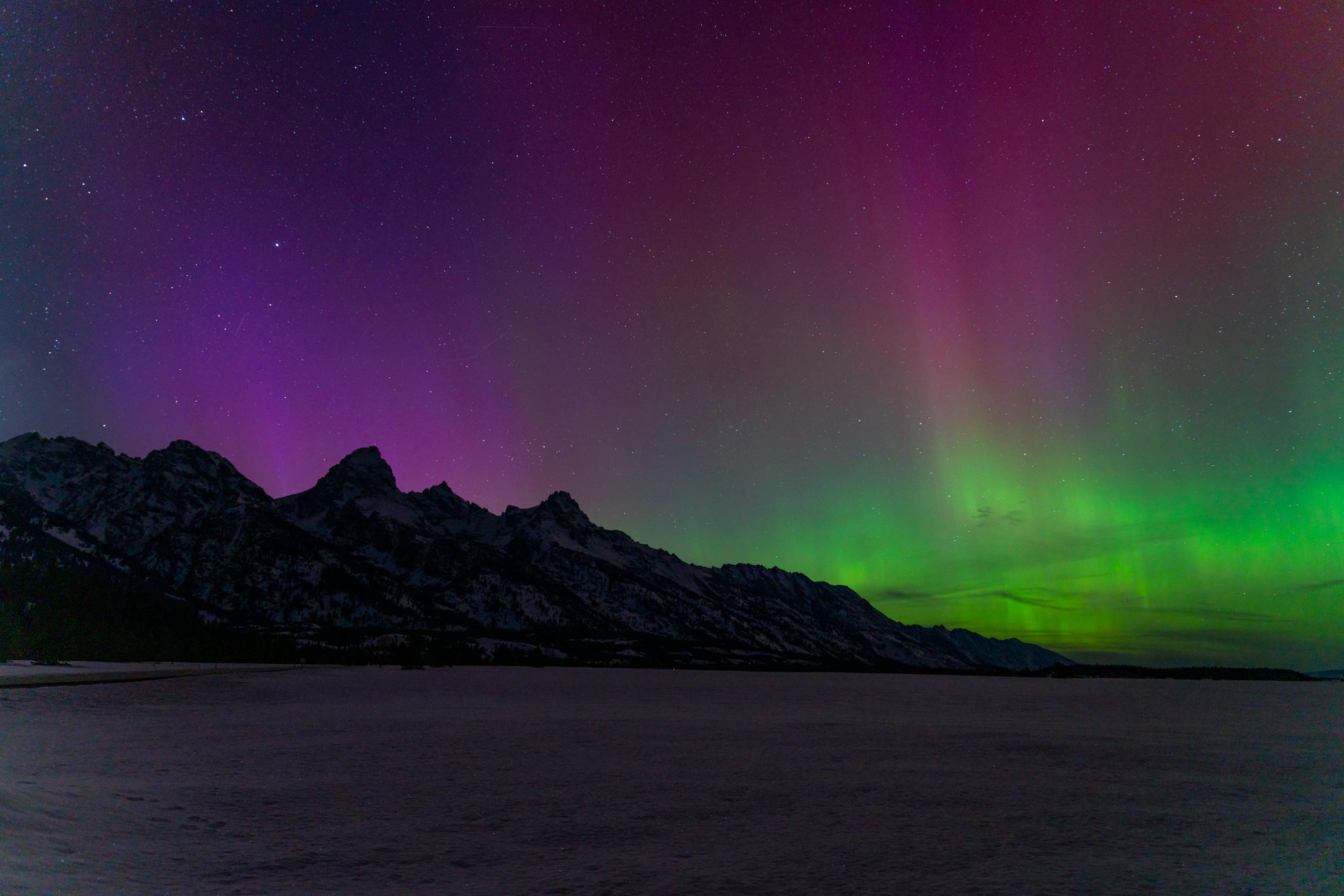 Purple and green aurora borealis dance in the sky above Grand Teton National Park