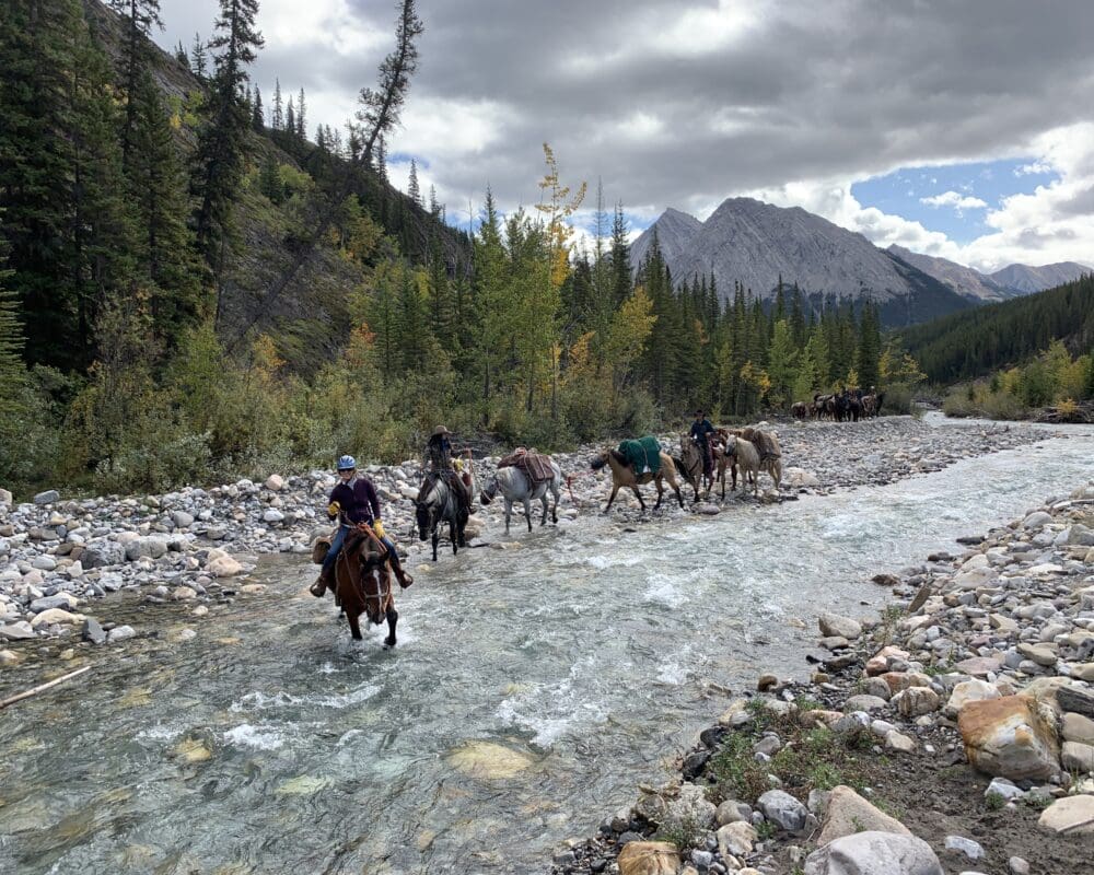 People on horses ford a river