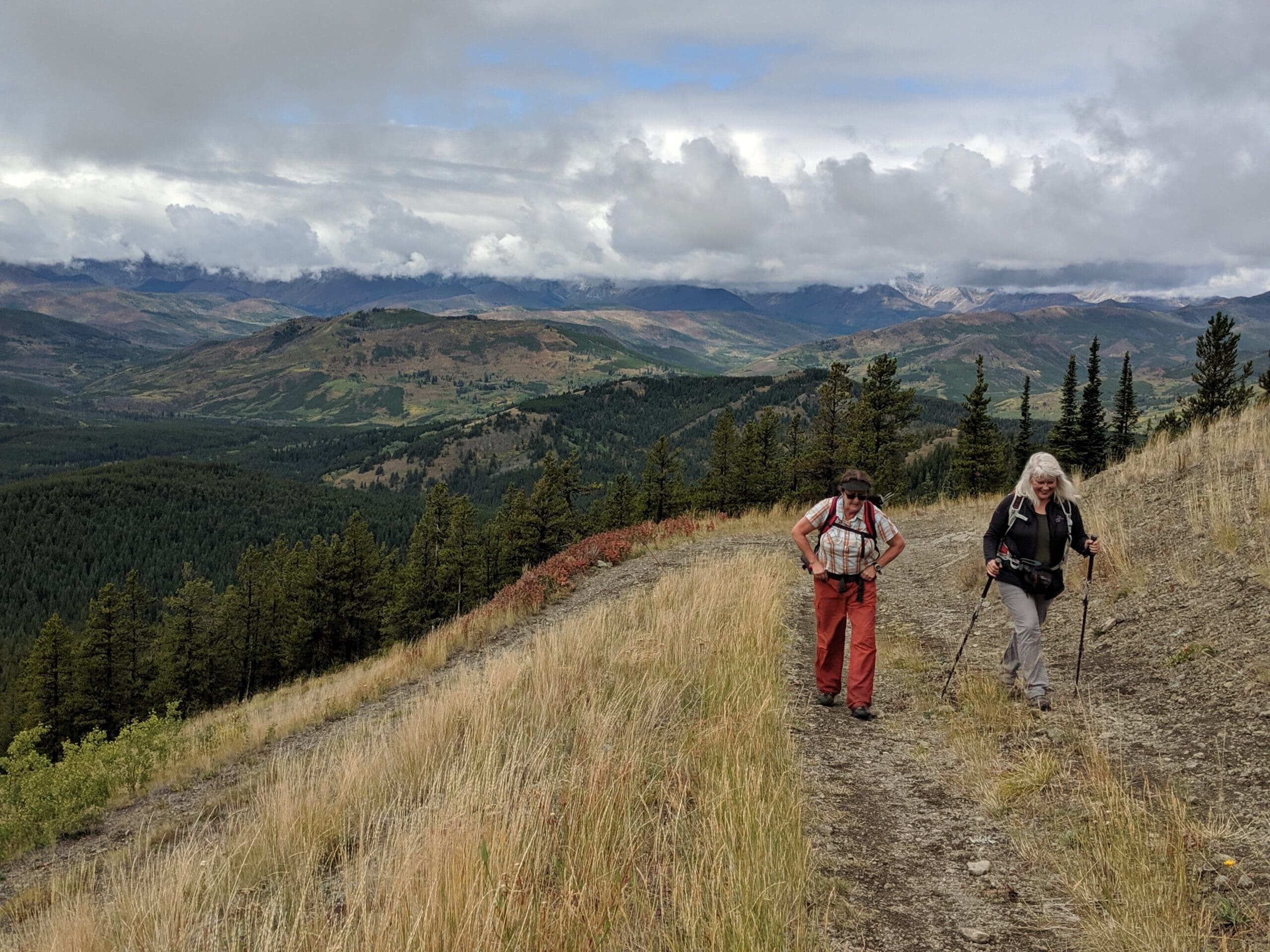 Two people walk up hill on a grassy slope in southeastern Alberta