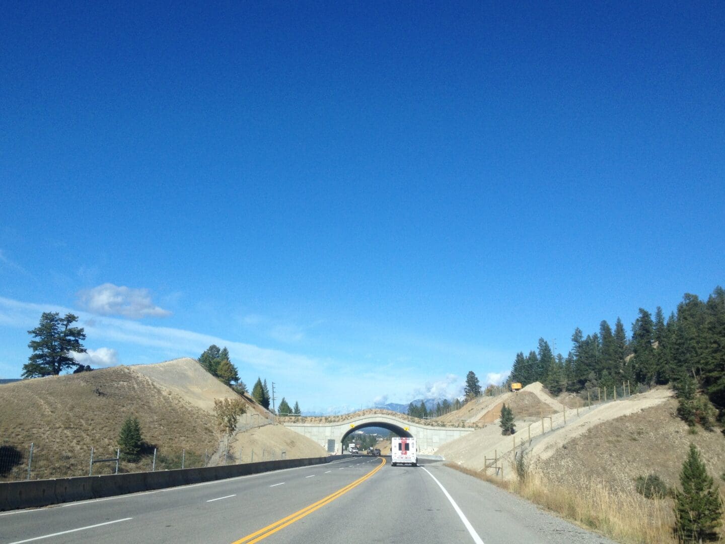A wildlife overpass stretches across the highway between tow hills.