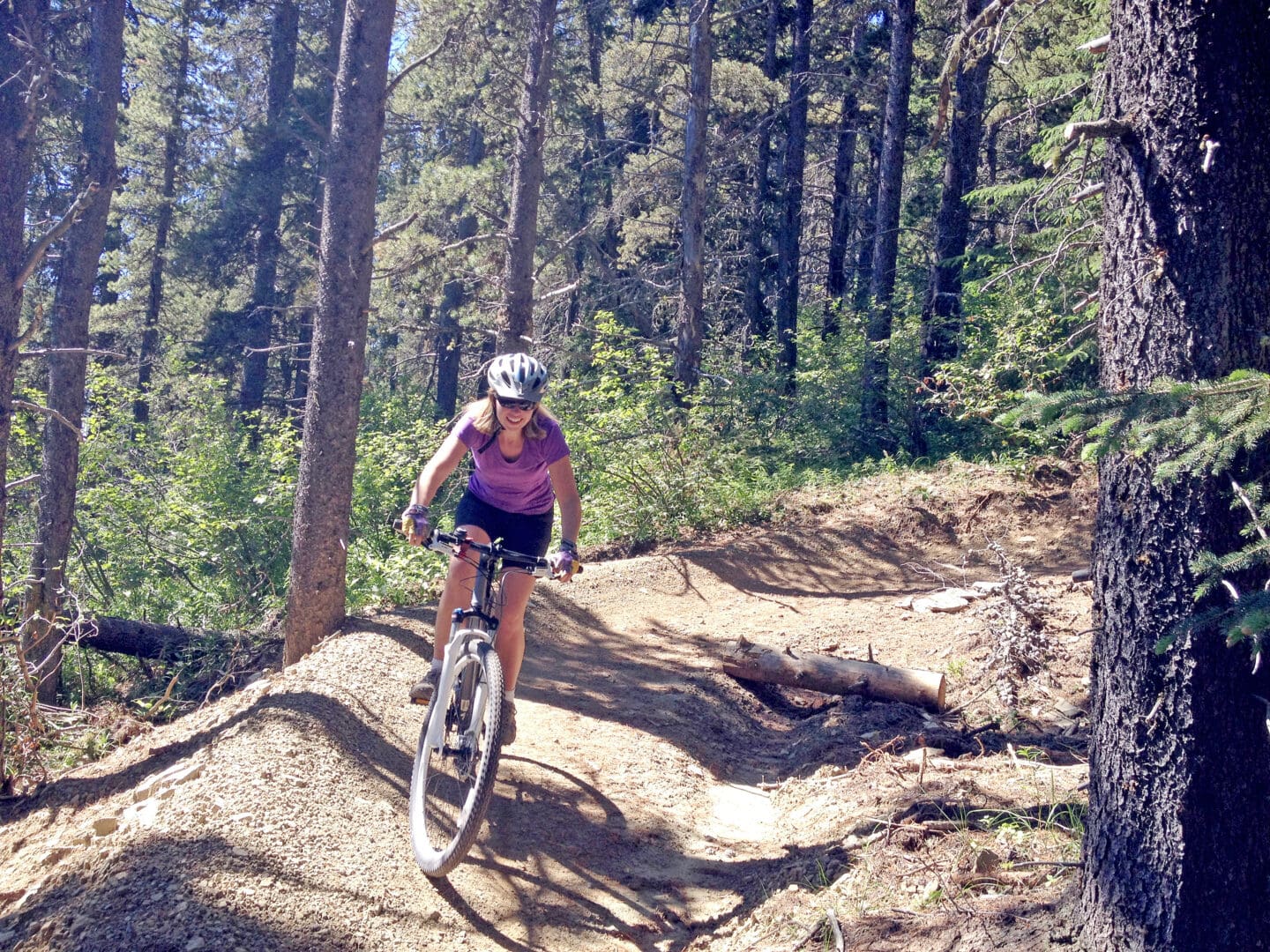 A person rides a mountain bike on a dirt trail through pine trees