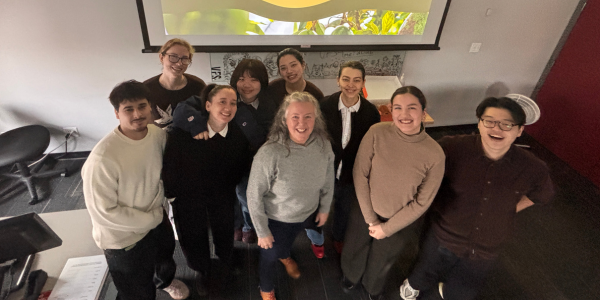 A group of students stand in front of a projector screen.